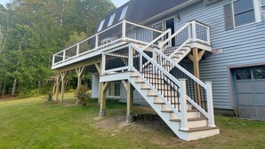 A two-story house with a covered outdoor staircase and a garage. - WATERFRONT ON BRANDY POND!  SLEEPS 20!! (Naples)