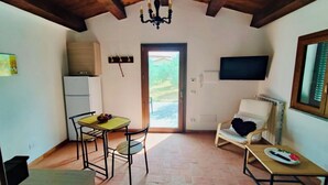 A cozy room with a dining area, a seating area, a television, and a window overlooking a garden. - Garin Knoll (Bolsena)