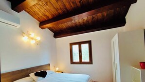 A bedroom with a wooden ceiling, a bed with white bedding, a window, and a white wardrobe. - Garin Knoll (Bolsena)