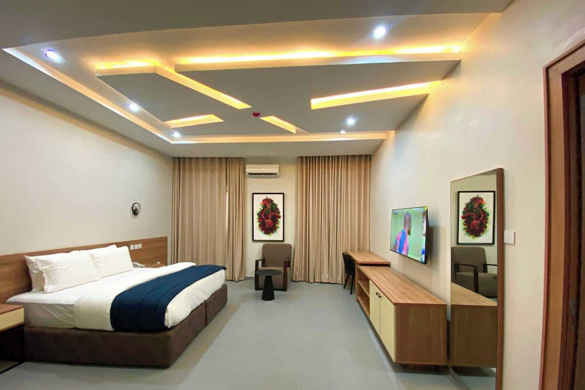 Une chambre d’hôtel moderne équipée d’un lit, d’un bureau, d’une télévision et d’un miroir.
