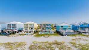 A row of beach houses with multiple stories, each featuring balconies and outdoor seating areas. - Gulf Front Duplex | Shared Pool | West Beach (Gulf Shores)