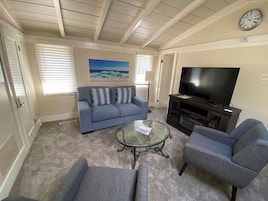 A living room with a blue sofa, a glass coffee table, and a television on a wooden stand.