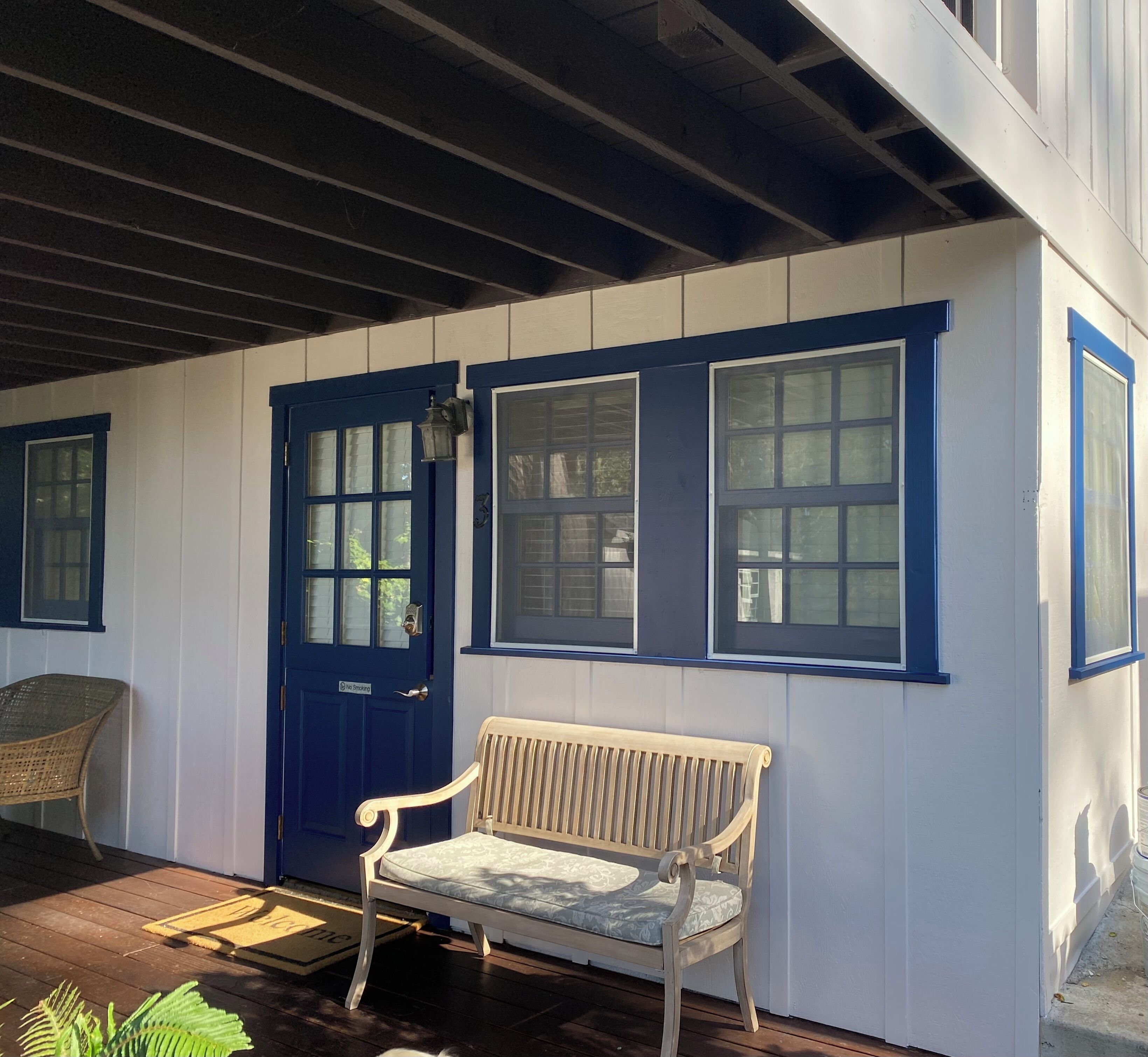 A covered porch with a bench, a door, and windows.