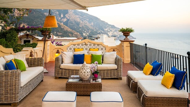 A terrace with wicker furniture, cushions, and a lamp, overlooking a coastal landscape. - Villa Maelle by My Villa Collection (Positano)