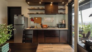 A modern kitchen with dark cabinetry, a stainless steel refrigerator, and a window overlooking the city. - Pha Boutique House (Xuan Huong - Da Lat)