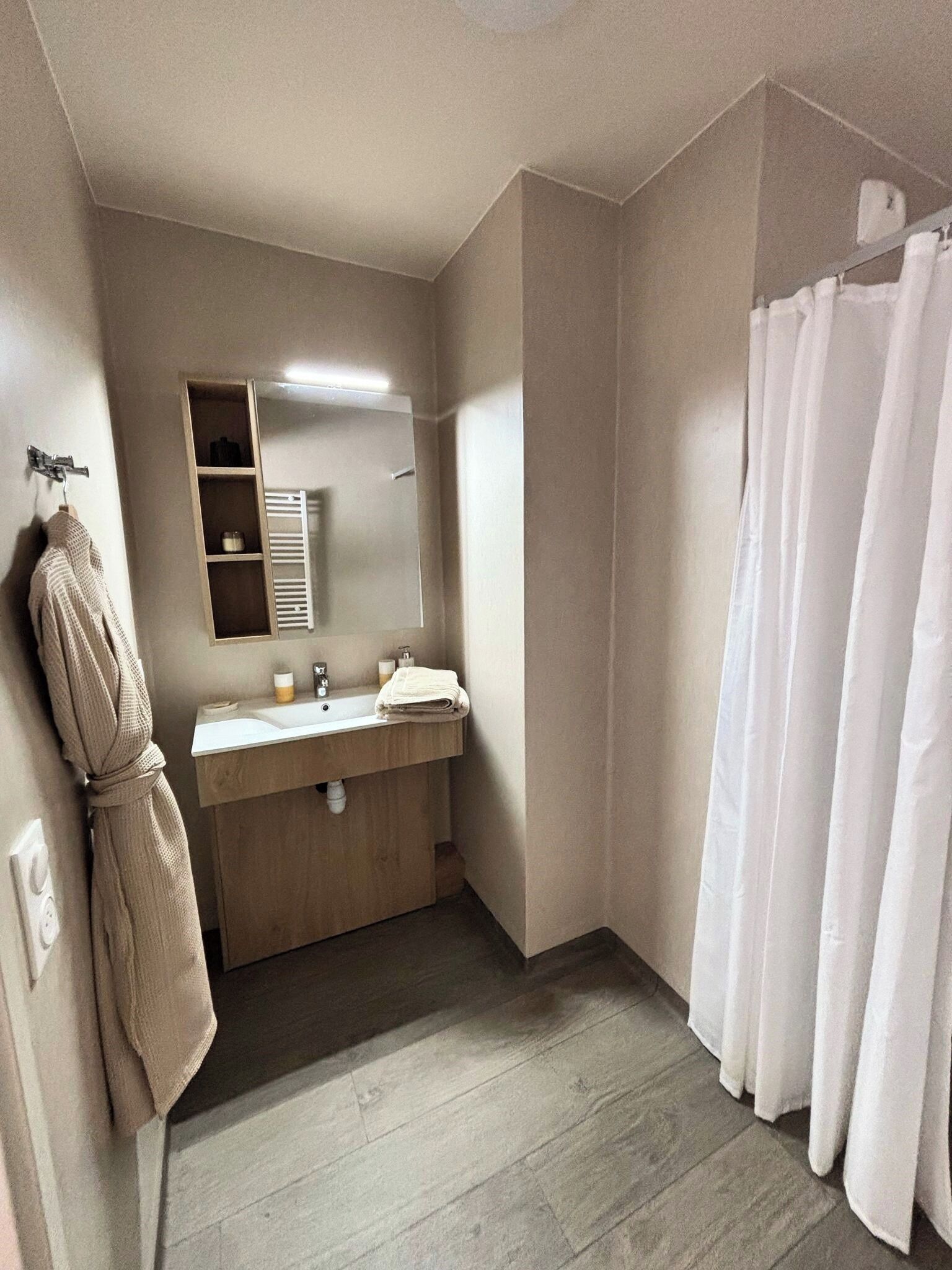 A bathroom with a wooden vanity, a towel rack, a mirror, and a shower curtain.