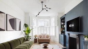 A living room with a sofa, armchair, coffee table, TV, fireplace, and decorative items. - Luxury 5-Bedroom, Central London Town House (Greater London)