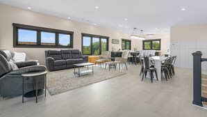 A modern living room with a sofa, armchair, and dining area with chairs and a table. - Easy Beach Access, Sleeps 12 (Old Orchard Beach)