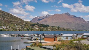 A marina with boats docked, a small wooden building, and a mountain in the background.