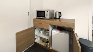 A compact kitchenette with a microwave, kettle, and refrigerator.