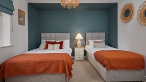 Een slaapkamer met twee bedden, een nachtkastje met een lamp en een hanglamp.