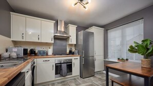 Een moderne keuken met witte kasten, roestvrijstalen apparatuur en een houten aanrecht.