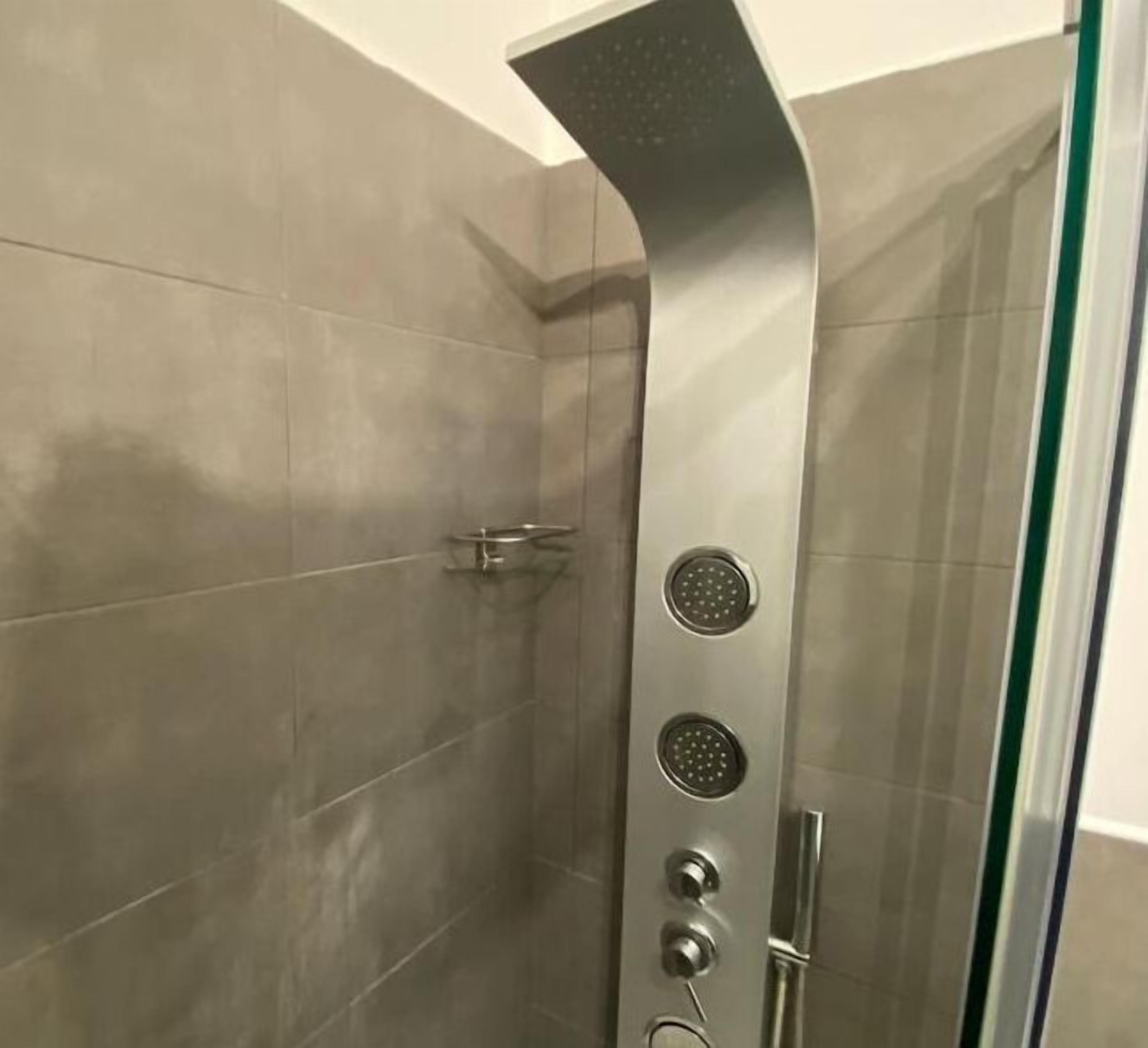Una ducha con diseño curvo, puerta de vidrio y tirador metálico.