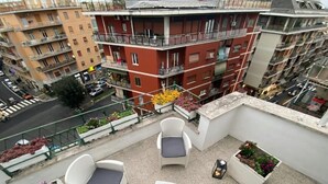 A balcony with outdoor seating, a view of adjacent buildings, and a street below. - Terrace Boutuque inn (Rome)