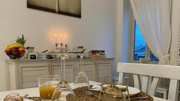 A dining area with a table set for two, featuring a fruit bowl, a candle, and a glass of orange juice. - Terrace Boutuque inn (Rome)