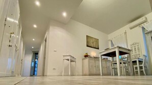 A spacious room with a high ceiling, recessed lighting, a white cabinet, and a dining area with chairs and a table. - Terrace Boutuque inn (Rome)