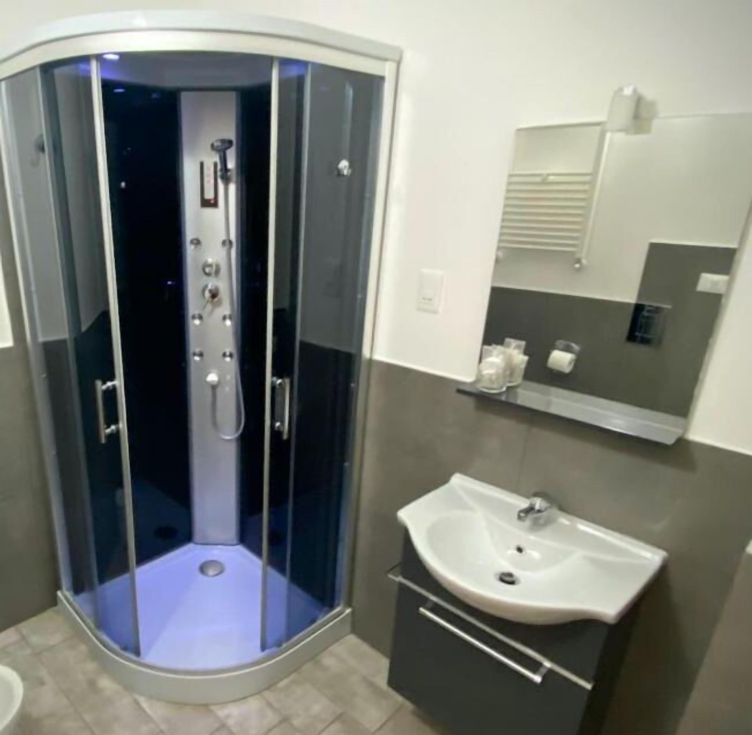 A bathroom with a glass-enclosed shower, a sink, and a mirror above it.