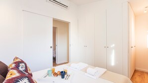 Una habitación de hotel con cama, una mesita de noche con provisiones para el desayuno, un armario y un equipo de aire acondicionado.