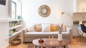 Una sala de estar moderna con un sofá, una mesa redonda de centro y un espejo decorativo en la pared.