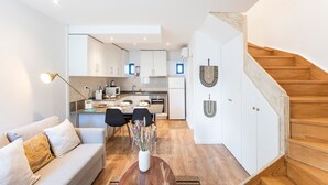 Un apartamento moderno con sala de estar, cocina y escalera.
