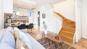 Una sala moderna con un sofá, una mesa de comedor y una escalera.