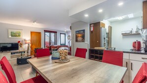 A modern kitchen with a refrigerator, stove, and microwave. There is a dining area with a wooden table and red chairs. - FLH Funchal Sissi Lanço with View (Funchal)