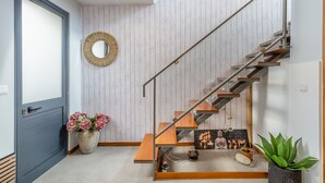 A modern interior with a staircase, a mirror, and a potted plant. - FLH Funchal Sissi Lanço with View (Funchal)