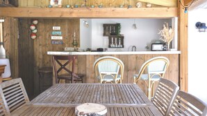 A wooden dining area with a table and chairs, a kitchen in the background, and a sign with 'Eat Drink Relax Be Happy' on the wall. - Exceptional house in Nieul-sur-Mer (Nieul-sur-Mer)