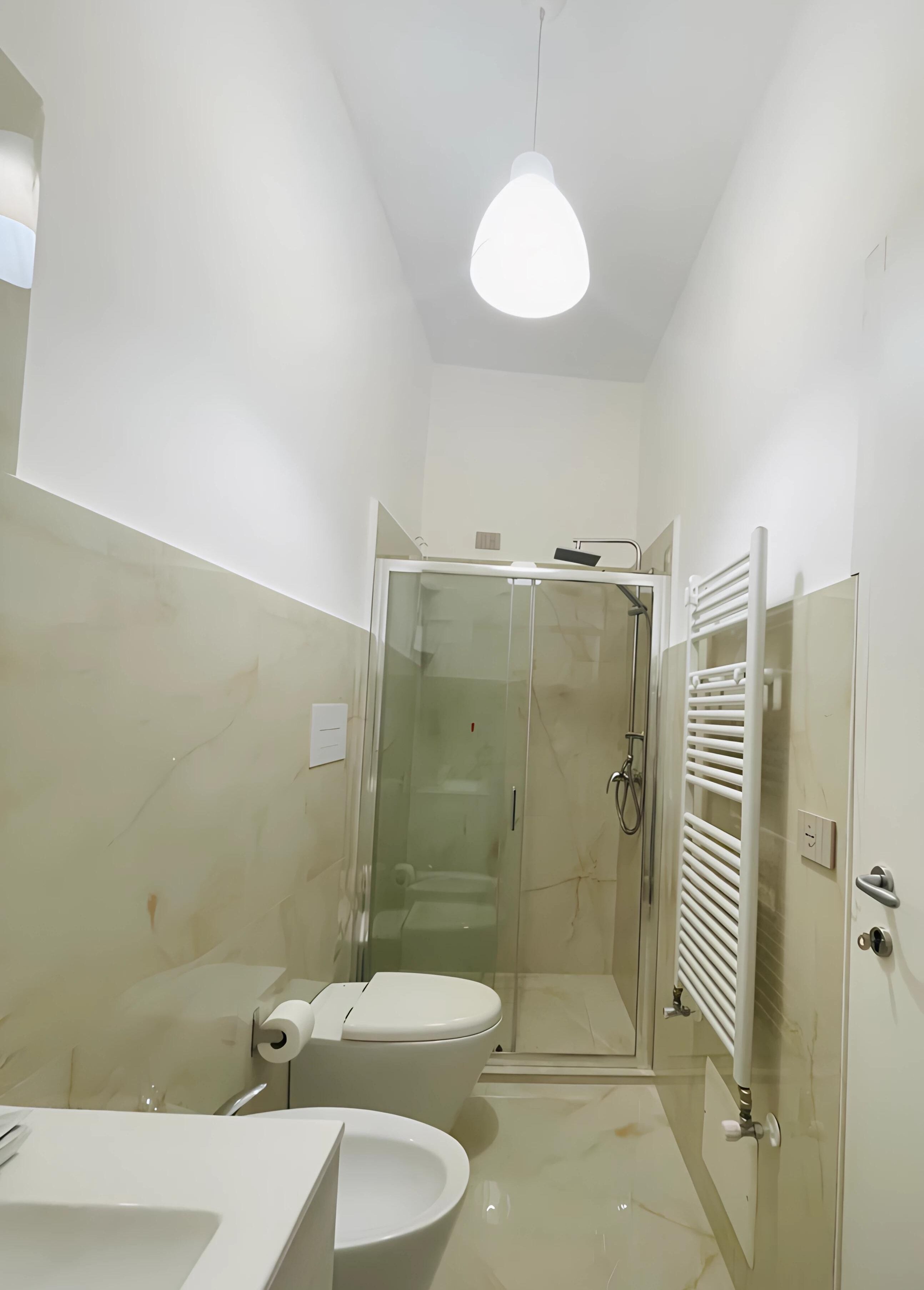 A modern bathroom with a glass-enclosed shower, a toilet, and a sink.