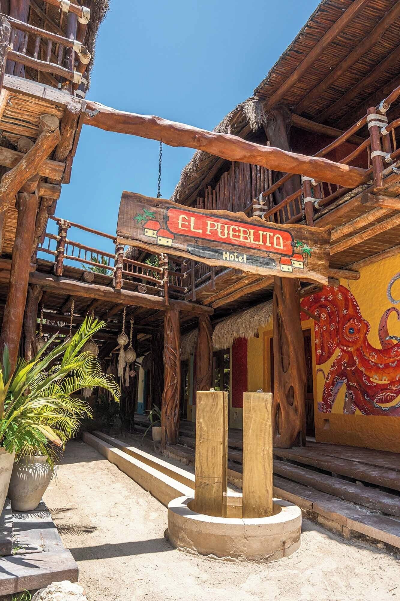 A rustic wooden building with a sign reading "EL PUEBLO Hotel".