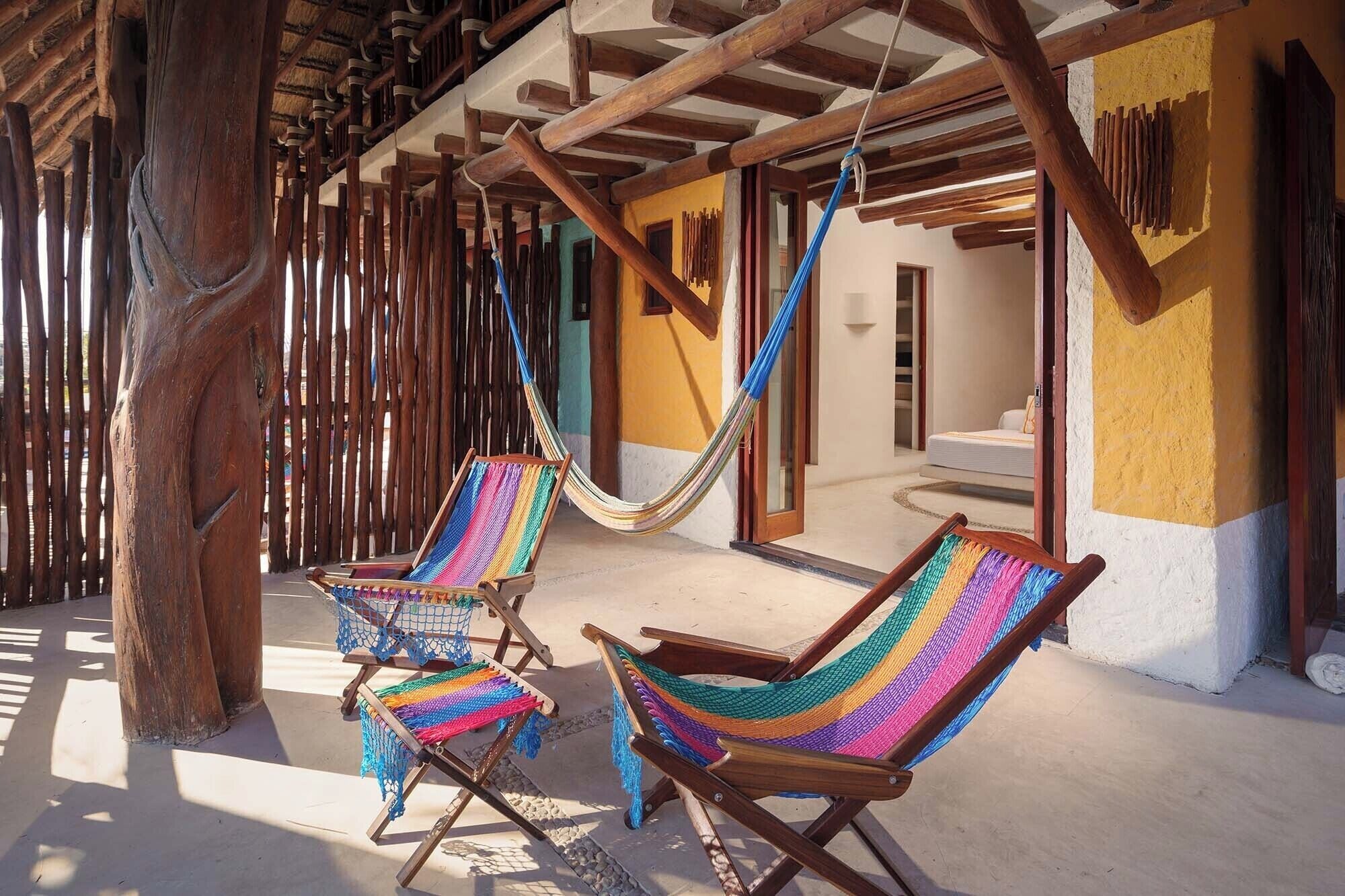 A wooden structure with two hammocks and a wooden chair.