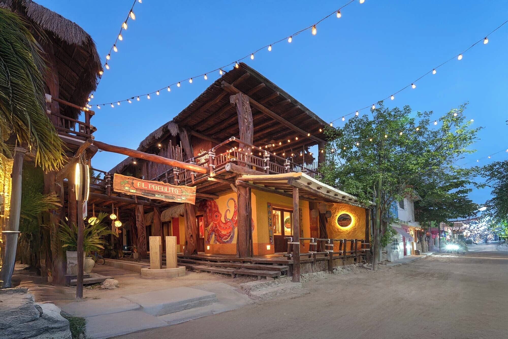A rustic hotel with a wooden facade, a balcony, and string lights.