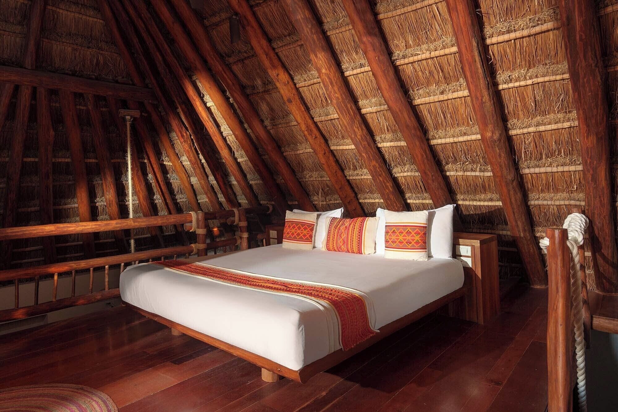 Ein Schlafzimmer mit einem hölzernen Bett, einem Reetdach und einer Holzbank.