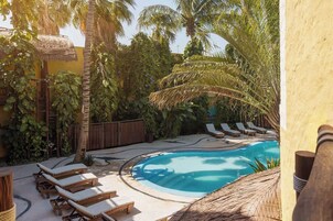 Zona de piscina con sillones de descanso y vegetación tropical.