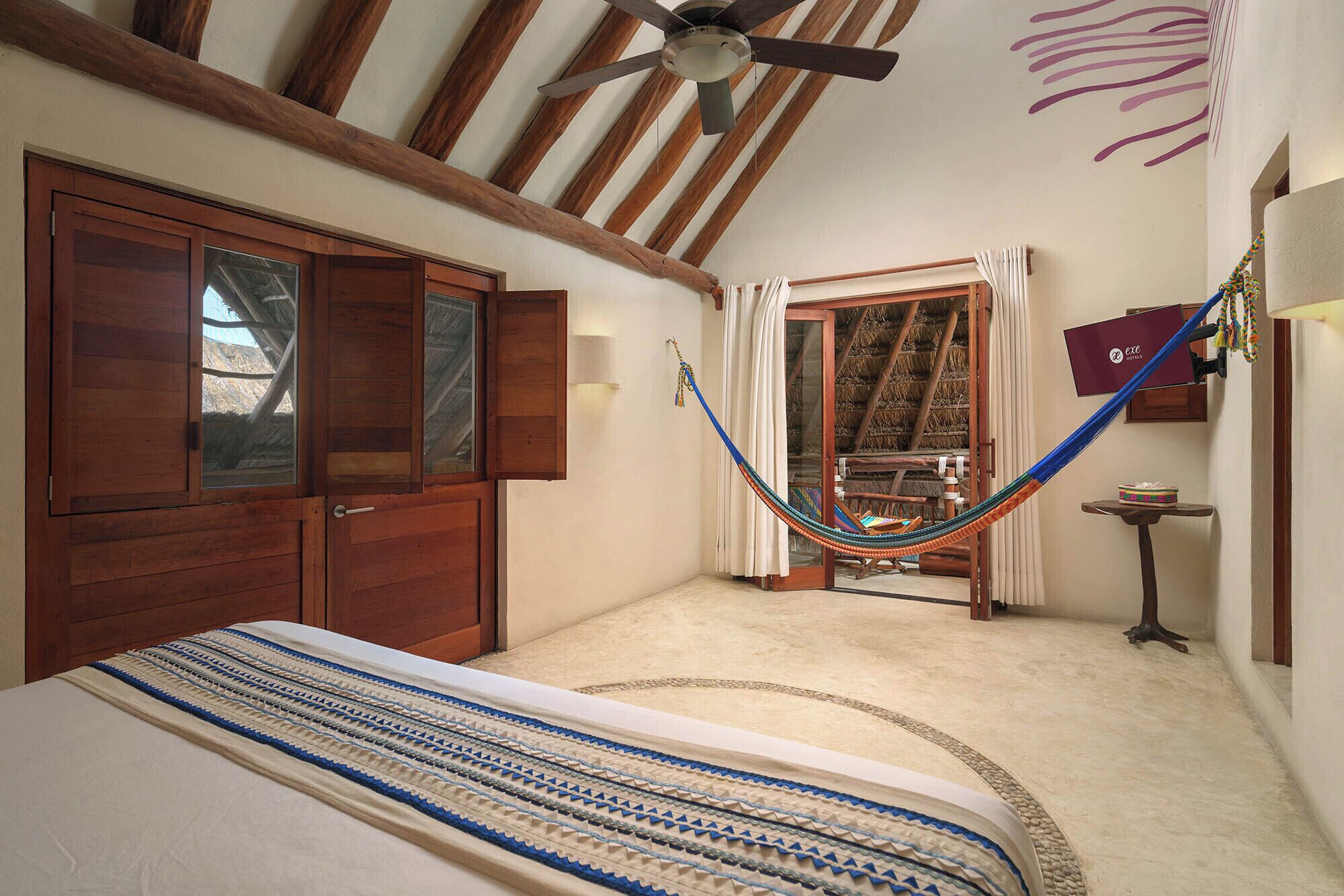 Un dormitorio con cama, armario de madera y una hamaca.