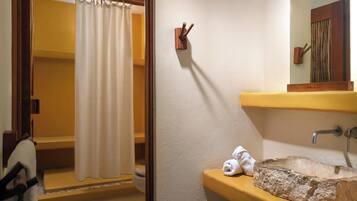 Une salle de bain avec un rideau de douche, un porte-serviettes en bois, un lavabo avec un receveur en pierre et un miroir au-dessus du lavabo.