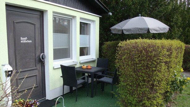 A small outdoor seating area with a table and chairs, a potted plant, and a hedge. - Vacation cottage in the countryside approx. 150m from the SpreewaldTherme-S (Burg (Spreewald))
