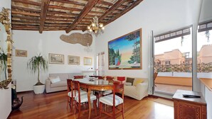 Un comedor con una mesa y sillas de madera, un sofá y un cuadro en la pared.