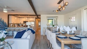 A modern kitchen with white cabinets, a dining area with a wooden table set for six, and a living room with a white sofa and blue cushions. - Scottsdale Heated Pool Sleeps 20, Gorgeous! Near Old Town (Scottsdale)