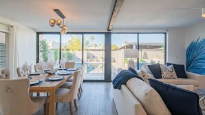 A modern living room with a dining area, large windows, and a view of the outdoors. - Scottsdale Heated Pool Sleeps 20, Gorgeous! Near Old Town (Scottsdale)