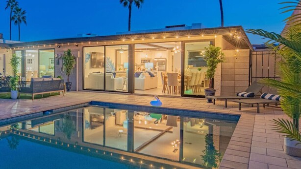 A modern house with a swimming pool, glass doors leading to a dining area, and outdoor seating. - Scottsdale Heated Pool Sleeps 20, Gorgeous! Near Old Town (Scottsdale)