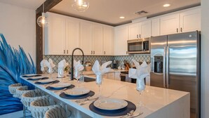 A modern kitchen with white cabinets, stainless steel appliances, and a central island with a dining setup. - Scottsdale Heated Pool Sleeps 20, Gorgeous! Near Old Town (Scottsdale)