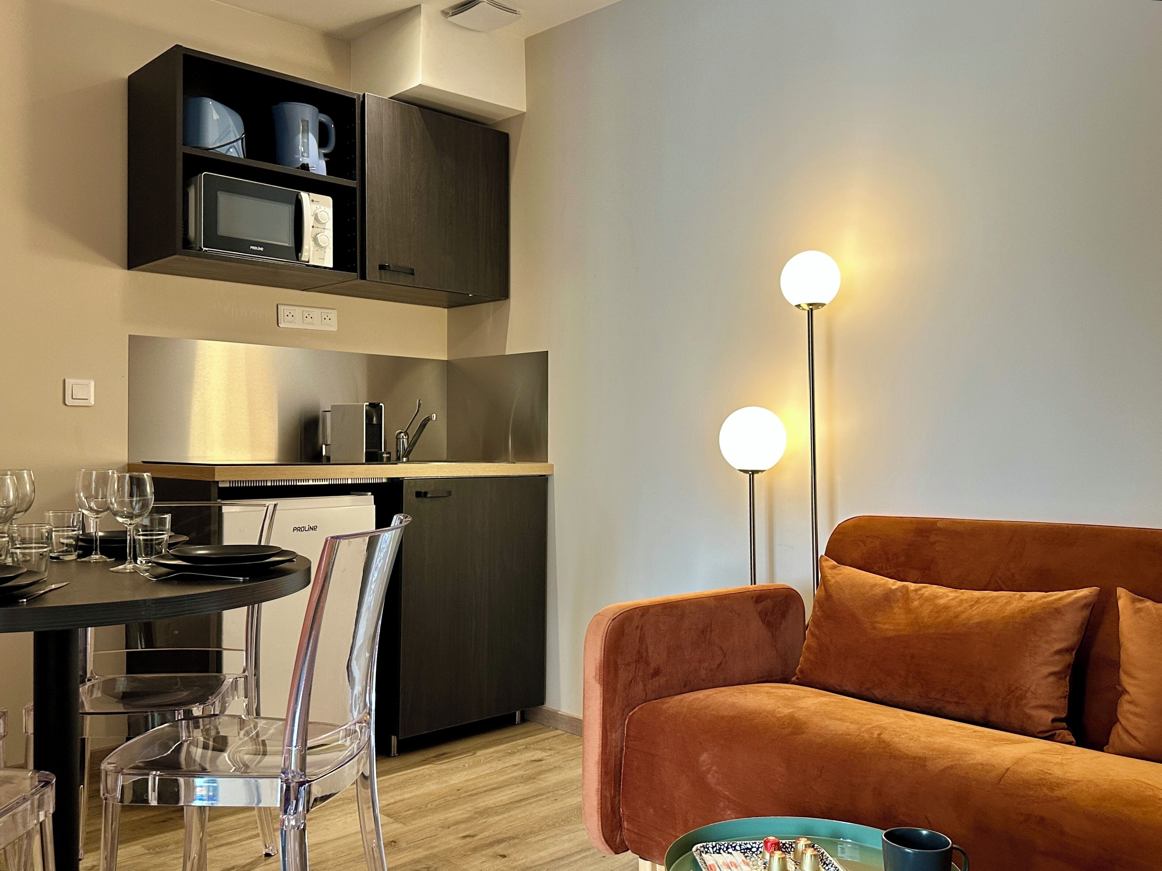 Eine moderne Küche mit Essbereich, einer Couch und einer Stehlampe.