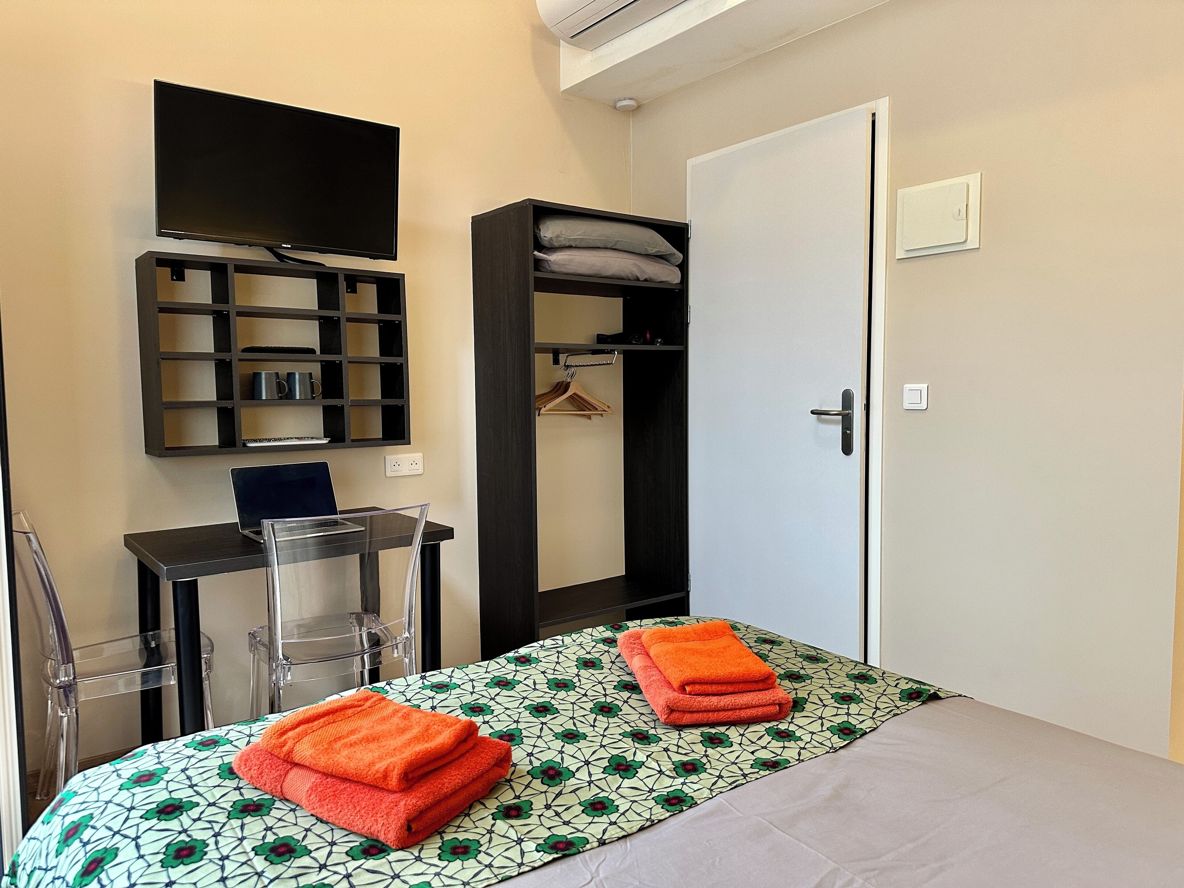 Un dormitorio con cama, escritorio, televisor y armario.