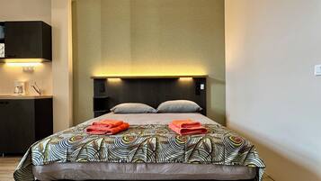 A modern hotel room with a large bed, a bedside table with a lamp, and a built-in wardrobe.