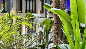 Un edificio moderno con ventanas amplias y un área de balcón con abundante vegetación.