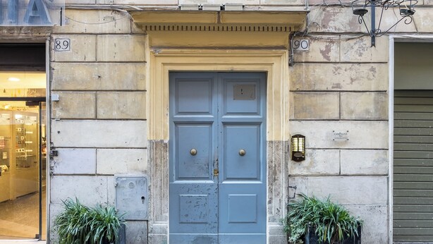 A double door with a small window above it, flanked by two potted plants. - JOIVY Flats Next To Fontana di Trevi (Rome)