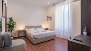 A modern hotel room with a bed, bedside tables, a desk, a chair, and a potted plant. - JOIVY Flats Next To Fontana di Trevi (Rome)
