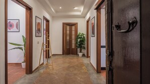 A hallway with wooden doors, framed artwork, potted plants, and a ladder. - JOIVY Flats Next To Fontana di Trevi (Rome)