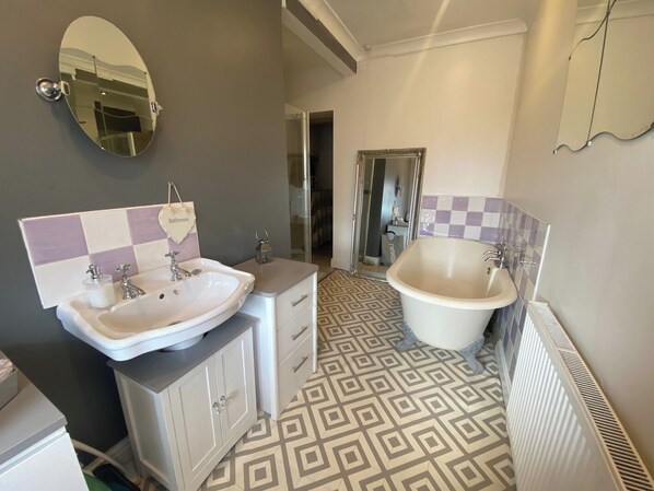 A bathroom with a large oval mirror, two sinks, a bathtub, and patterned floor tiles. - Welsh Retreat With Stunning Views, Sleeps Upto 4 (Mountain Ash)